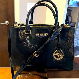 Michael Kors black patent leather handbag with gold hardware.